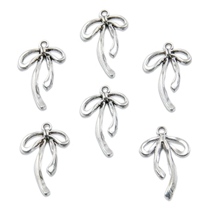 Macro shot of six antique silver bow-shaped alloy pendants with hanging loops for jewelry