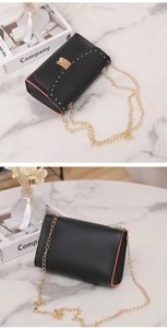 Detail of black rivet chain bag showing red contrast edge and golden push-lock closure