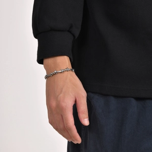 Detailed close-up of a silver barbed wire style cuff bracelet worn on a male wrist