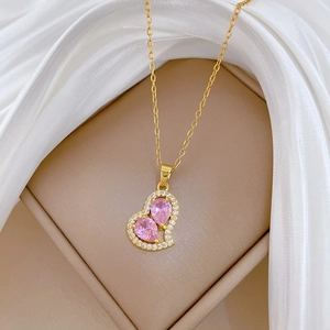 Macro view of gold necklace featuring pink heart pendant on white silk background