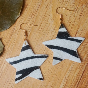 Détail de boucles d'oreilles étoiles en fausse fourrure zébrée avec crochets dorés
