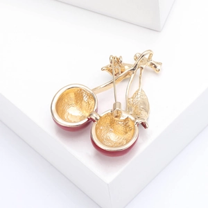 Macro shot of red enamel cherry brooch with gold metal frame and pin closure detail