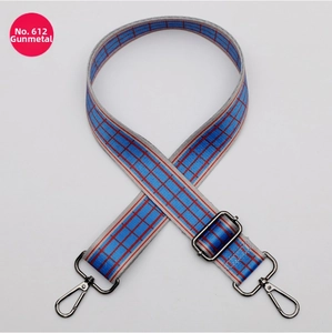 Detail of adjustable wide canvas bag strap with red and blue checkered pattern and gunmetal hooks