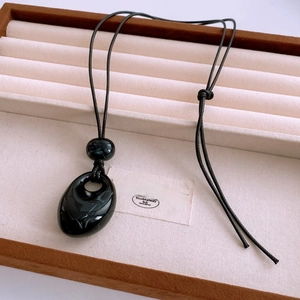 Macro view of water drop acrylic pendant with marble texture on wax rope necklace
