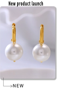 Detail of elegant white round pearl pendant with golden U-shaped stainless steel hook