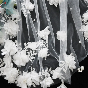 Macro shot of bridal veil featuring 3D silk flowers, delicate embroidery, and white pearls