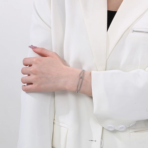 Detail of silver double-layered stainless steel bracelet with knot charm on model wrist