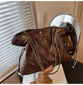 Detailed shot of brown quilted tote bag with gold chain strap in a modern interior setting