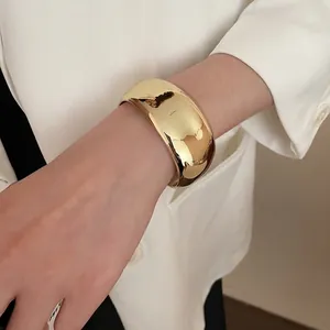 Bracciale rigido geometrico irregolare in oro lucido indossato con giacca bianca