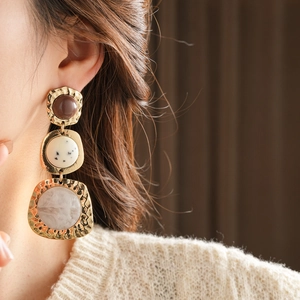 Macro shot of model wearing vintage gold hammered earrings with resin and stone inlays
