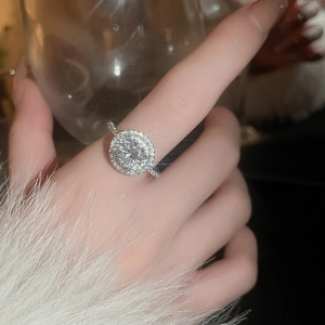Close-up of sparkling silver halo zircon ring worn with elegant white autumn sweater