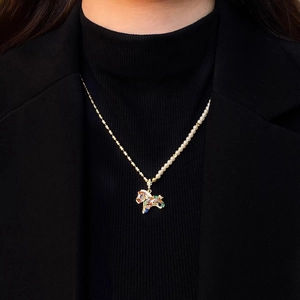 Detail of gold horse pendant with zircon and asymmetrical pearl chain necklace