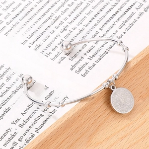 Detailed view of silver stainless steel cuff bracelet with a St. Benedict religious medal