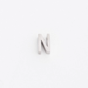 Macro detail of silver-colored stainless steel letter N pendant bead with matte finish