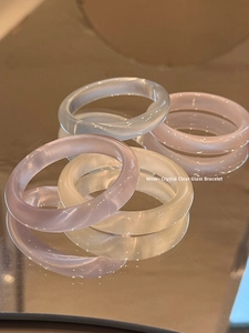 Gros plan de bracelets translucides lisses rose, blanc et bleu en pierre œil de chat sur miroir