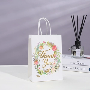Detail of white paper gift bag with floral wreath and golden Thank You lettering
