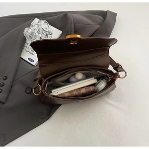Deep brown leather shoulder bag detail showing interior capacity and zipper pocket