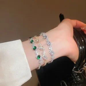 Set of three fashion zircon cuff bracelets in emerald and gold on a model's wrist