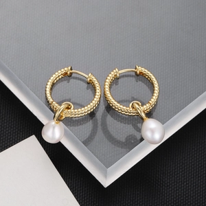 Detailed close-up of textured gold hoops with elegant white pearl teardrop pendants