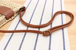 Close-up of cream paper rope weave detail with brown leather strap and metal buckle