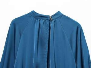 Detail of high neck silk satin dress with back pleats and decorative gold buttons