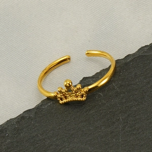 Bague couronne dorée ajustable en acier inoxydable minimaliste sur un tissu texturé