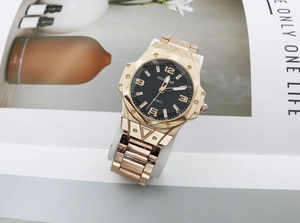 Macro detail of luxury gold quartz watch showing textured black dial and metal strap