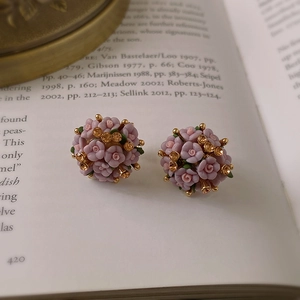 Macro shot of pink ceramic flower cluster earrings with rhinestones on a vintage book