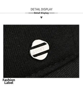 Dettaglio macro del logo SPORT in metallo argentato sul berretto in twill nero