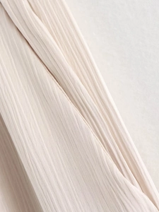 Détail macro du tissu plissé beige et couture latérale délicate sur le costume d'été