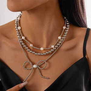 Detailed view of triple-layered faux pearl and silver beaded necklace with bow pendant