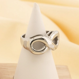 Detailed view of a silver infinity symbol ring displayed on a white conical jewelry stand