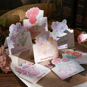 Close-up of assorted watercolor flower greeting cards with romantic phrases on a wooden desk