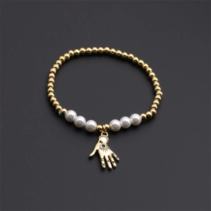 Detail of gold beaded chain featuring white pearls and a Fatima hand evil eye charm