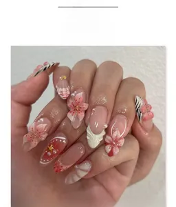 Close-up of pink press-on nails with 3D floral accents, pearls, and zebra patterns
