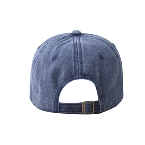Détail de la casquette en denim bleu délavé montrant la boucle métallique réglable