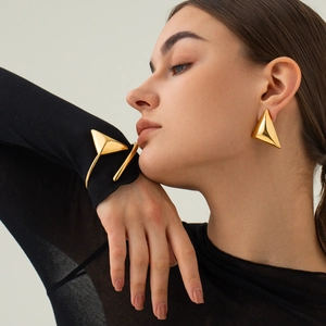 Detailed close-up of 18k gold-plated stainless steel triangle earrings and cuff bracelet