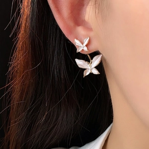 Élégantes boucles d'oreilles double papillon dorées avec émail blanc sur l'oreille
