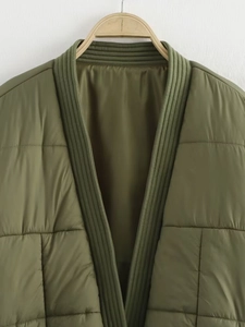 Nahaufnahme der armee-grünen Steppjacke mit V-Ausschnitt und Karomuster-Verarbeitung