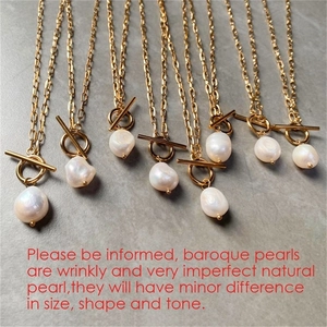 Detail of baroque pearl necklaces with golden T-bar clasps on a grey surface