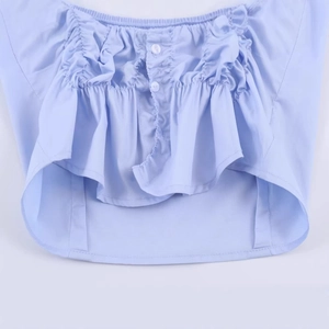 Close-up of light blue pleated poplin shirt featuring ruffled edges and white buttons