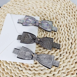 Detailed view of three bow spring hair clips with sparkling rhinestone inlay in various colors