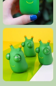 Macro shot of green stress relief slug toy with pop-out eyes being squeezed by a hand