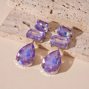 Dettaglio macro di orecchini di cristallo viola con pendenti a goccia e quadrati
