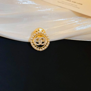 Close-up of gold brooch with white pearls and sparkling crystal bow-shaped design