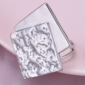 Detailed view of silver square ring featuring unique hammered texture on a ceramic surface