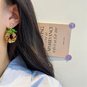 Detailed view of handmade beaded Christmas wreath earrings worn by a model