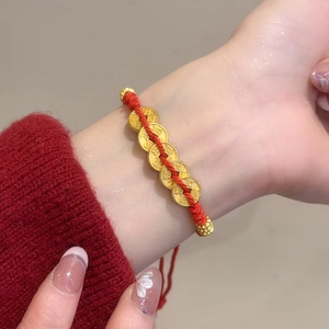 Detail of red woven bracelet with five golden fortune coins on a female wrist