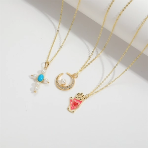 Détails de trois colliers dorés avec pendentifs croix, lune et main de Fatma