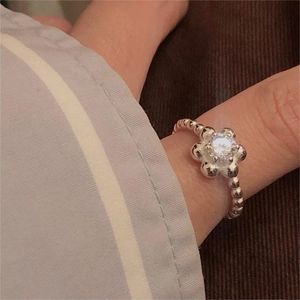 Macro shot of 925 silver beaded flower ring with sparkling zircon stone on a model's finger